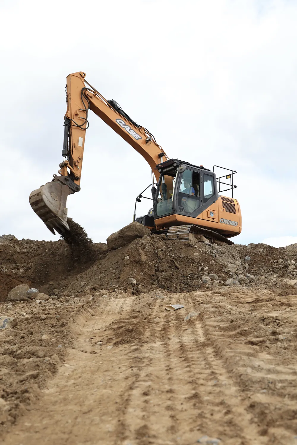 Excavator digging along an earth bank on a graded site