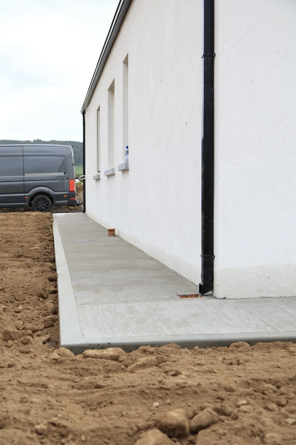 Newly laid concrete path around the wall of a house
