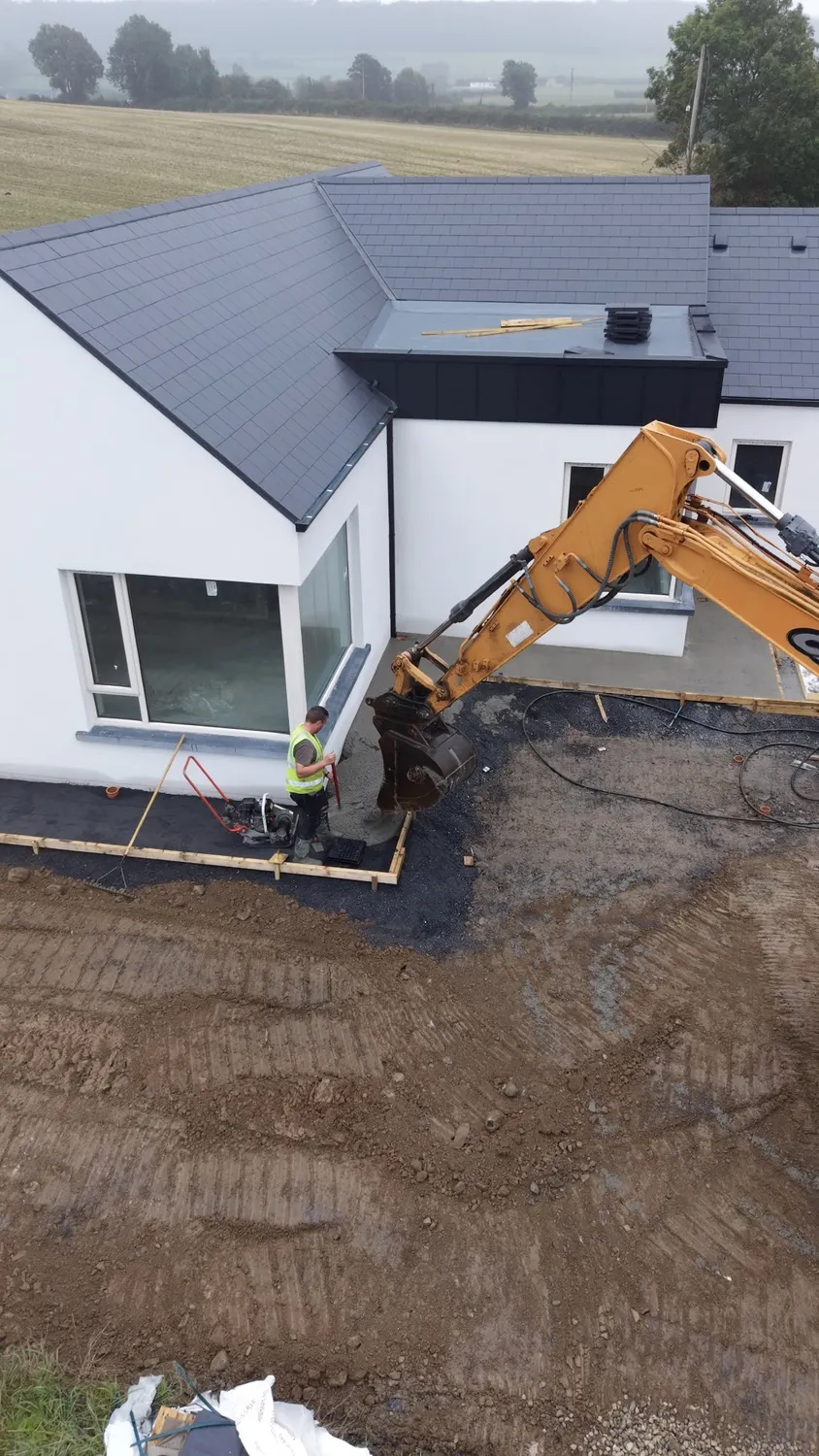 Elevated view of an excavator working beside a new home