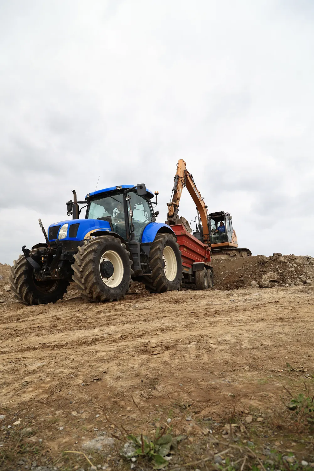 Tractor and excavator moving soil over an open site