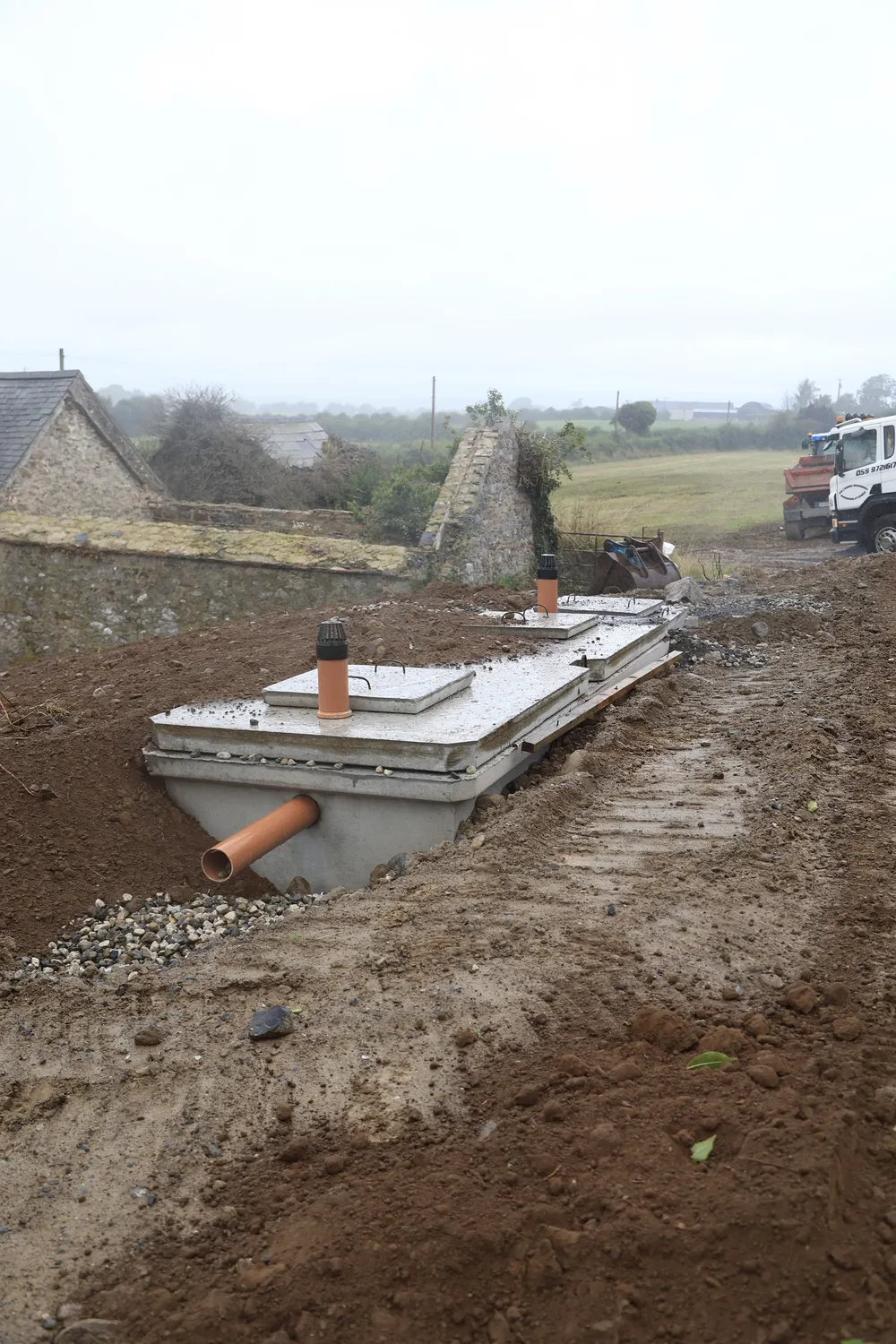 Drainage pipe and excavator beside a prepared house site