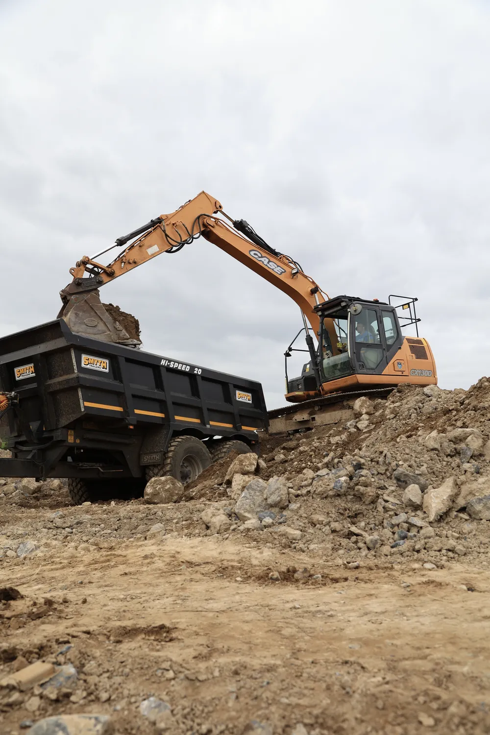 Excavator loading a tipper lorry on a cleared construction site