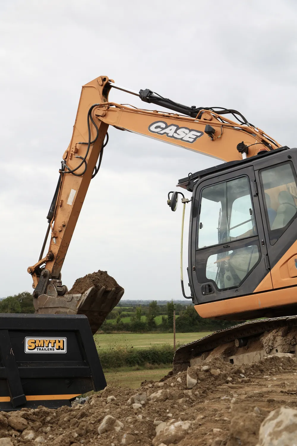 Excavator bucket digging into a raised bank of soil