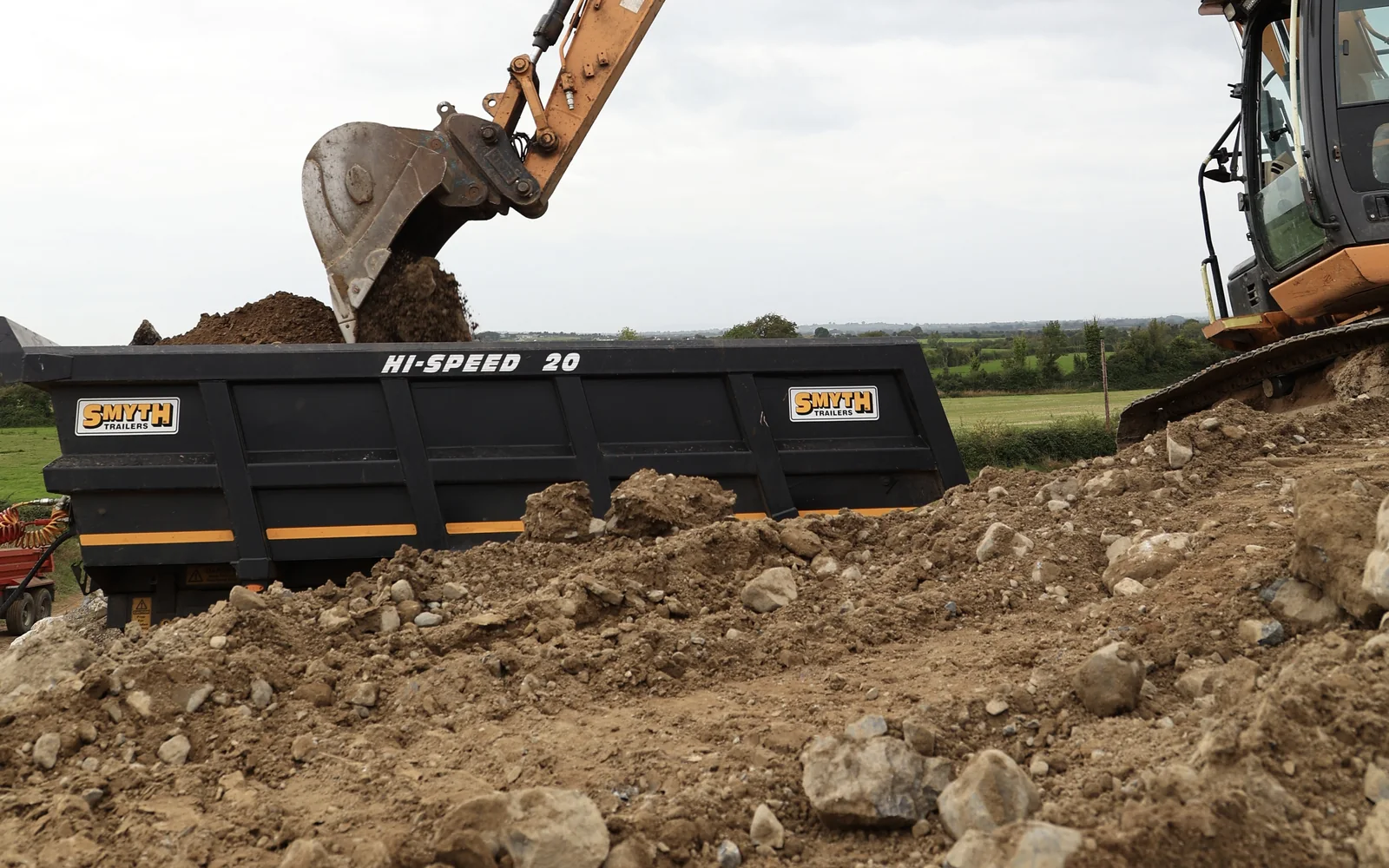 Excavator digging and loading soil into a site dumper during excavation works in Carlow