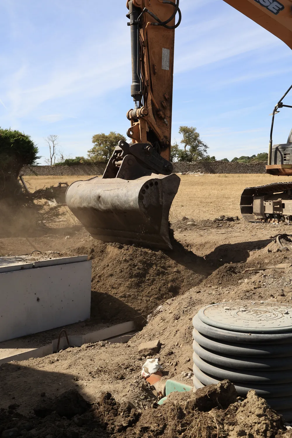 Excavator working next to a concrete tank and soil trench
