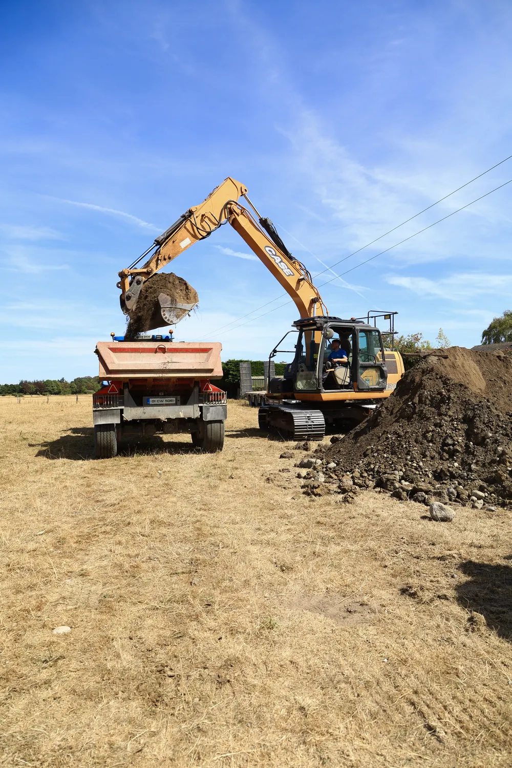 Excavator placing dug material into a trailer on a dry site