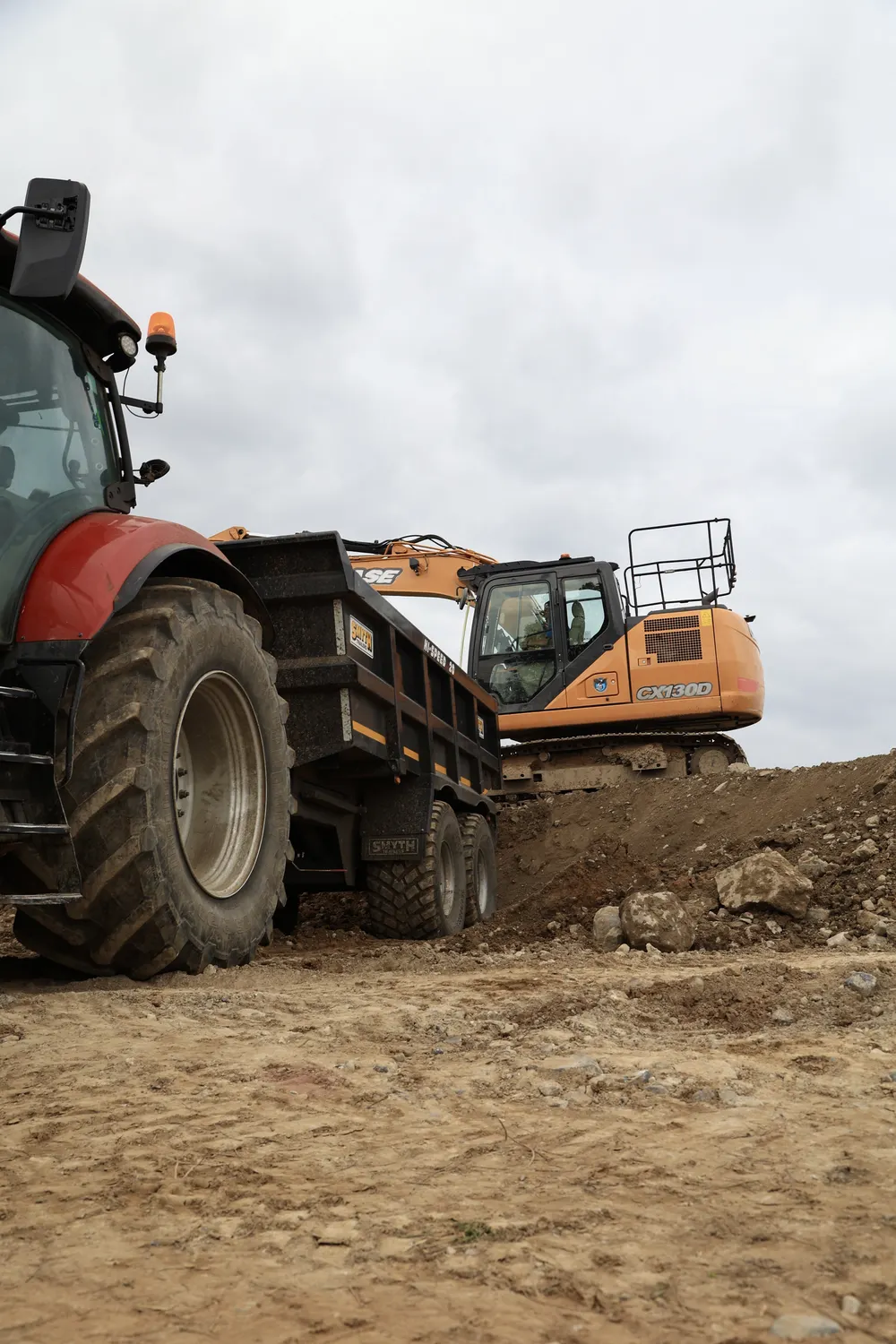 Tractor and excavator on prepared ground during earthmoving works