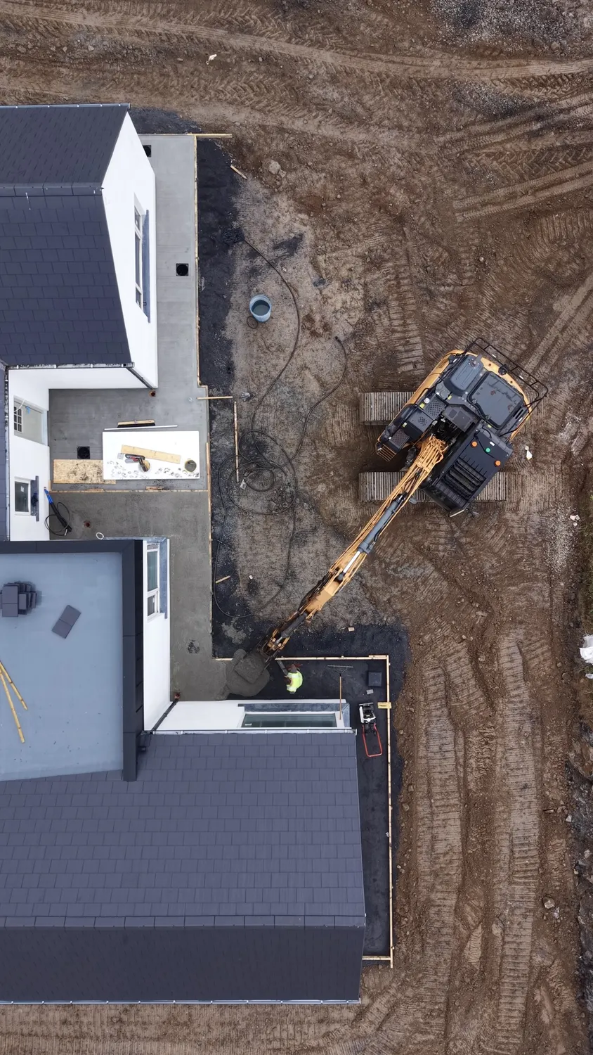 Top-down view of machinery and graded soil around a new house