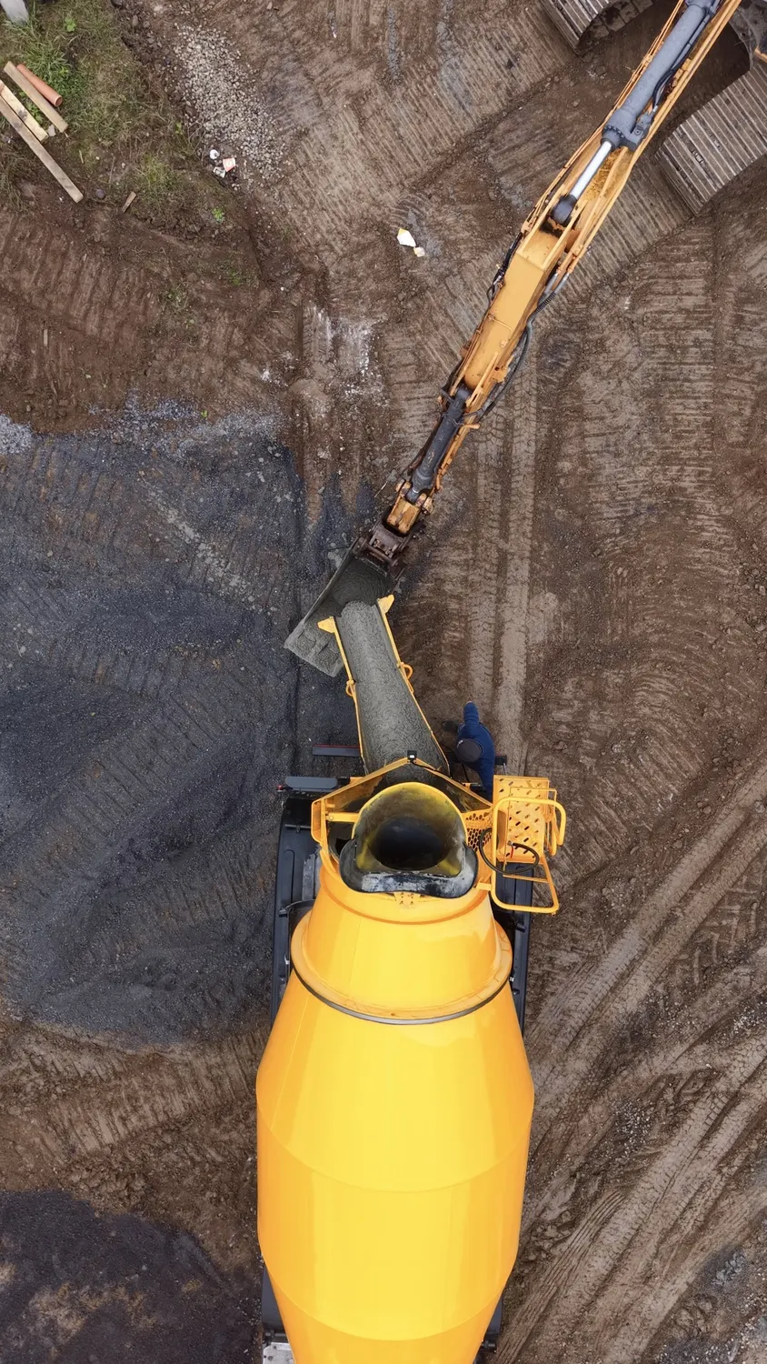 Overhead view of an excavator and round tank beside a house