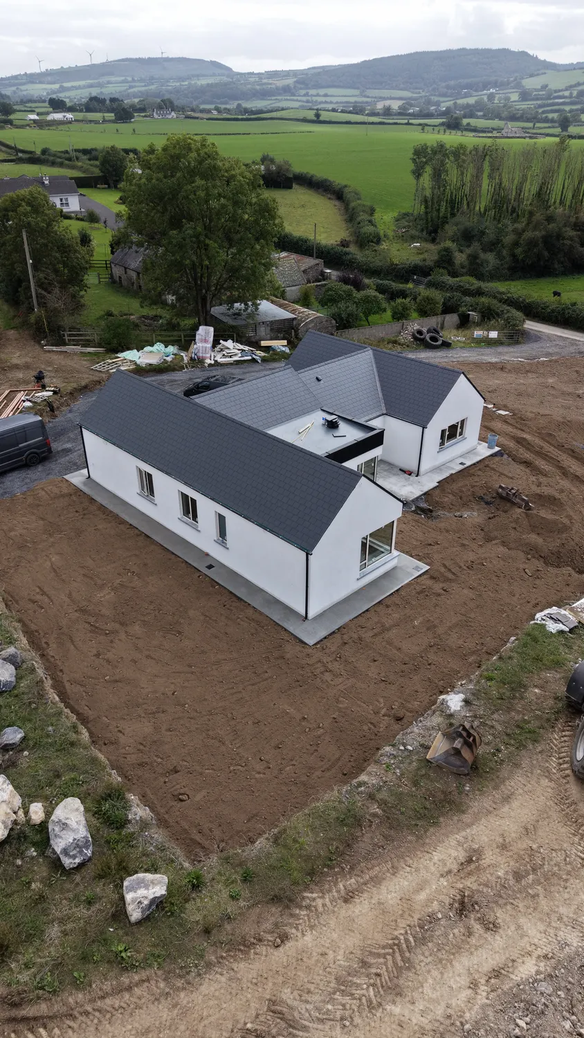 Aerial view of a newly built house with graded soil around its perimeter