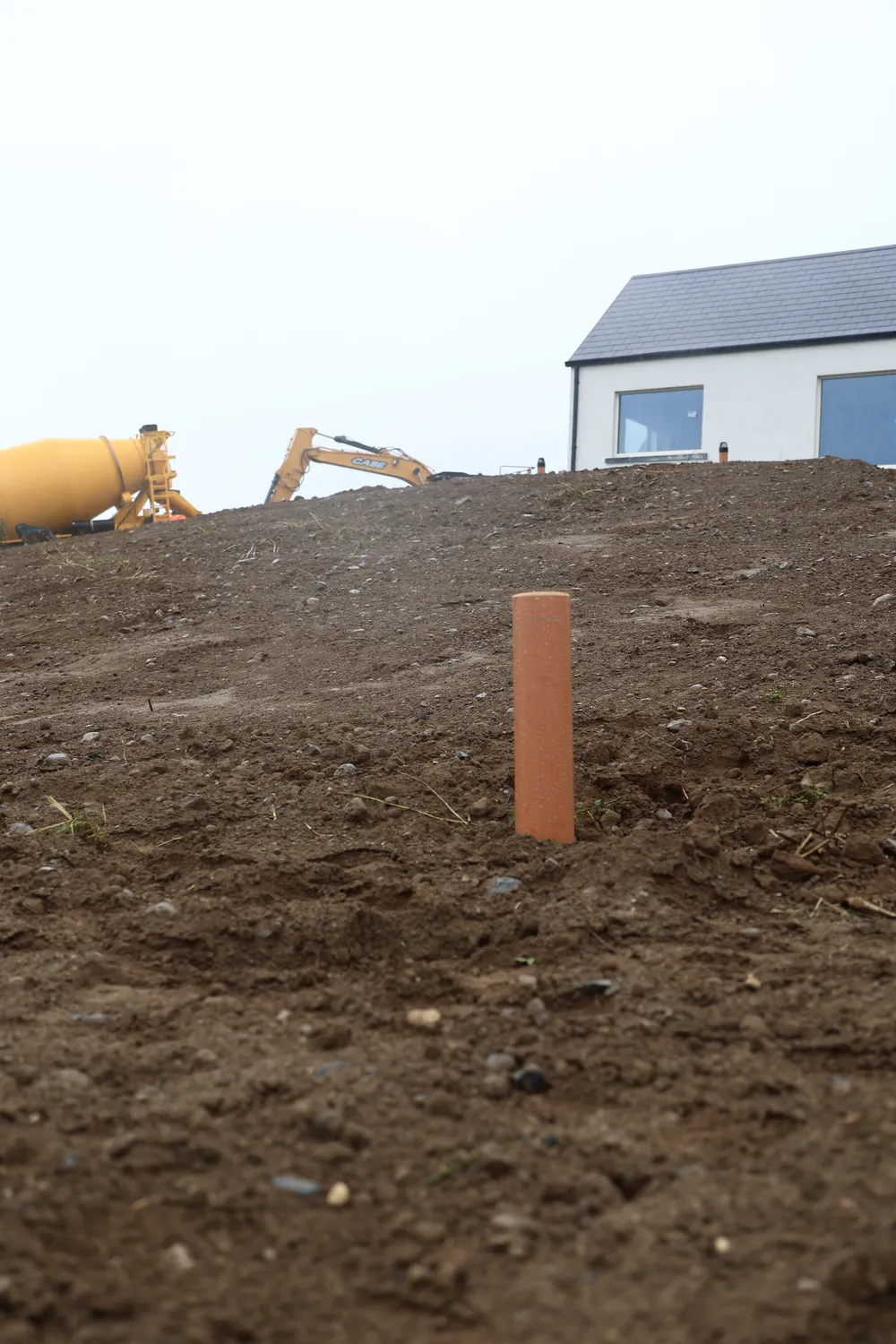 Graded earth and a marker post near a newly built home