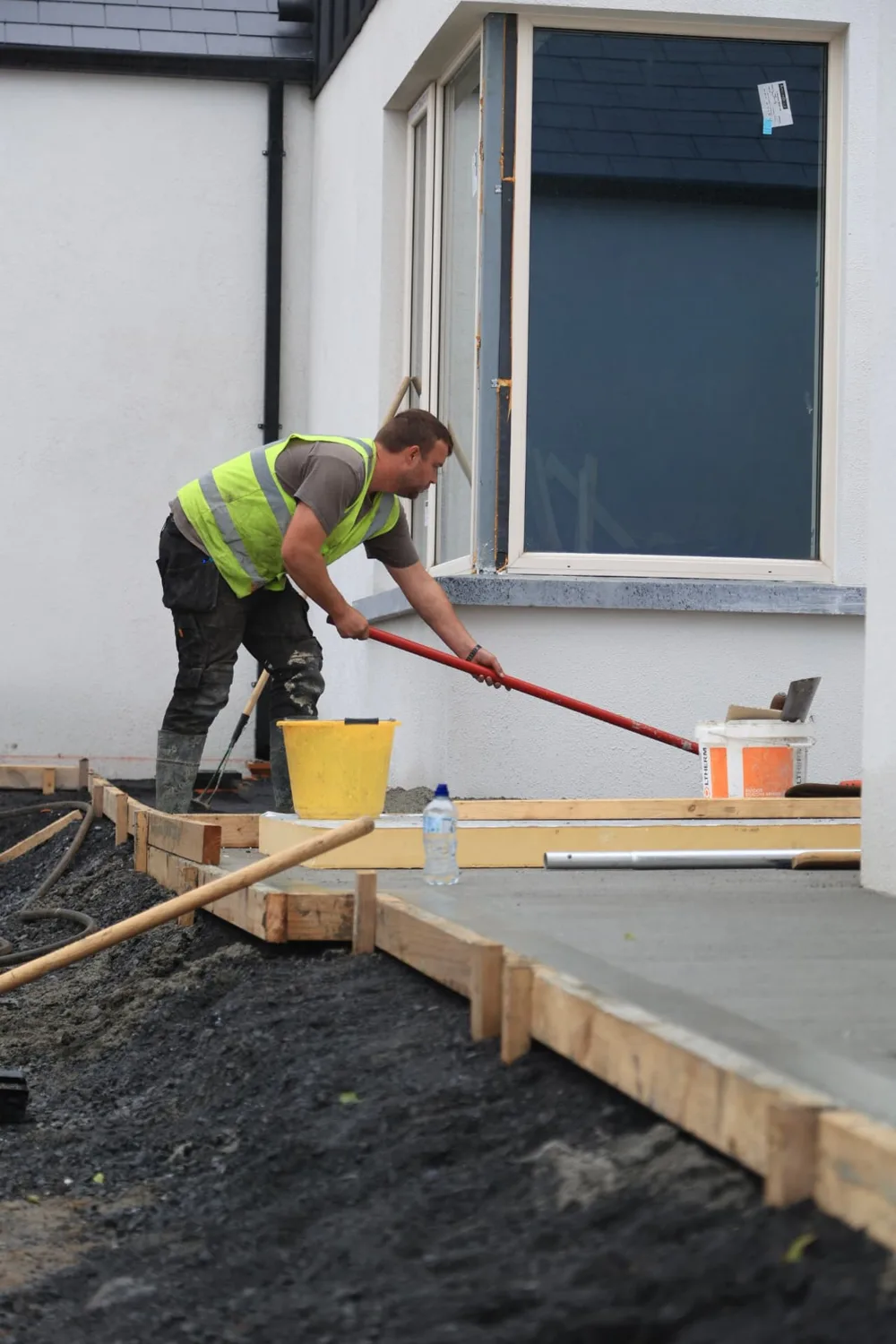 Groundworks worker screeding a fresh concrete slab at a house in Carlow