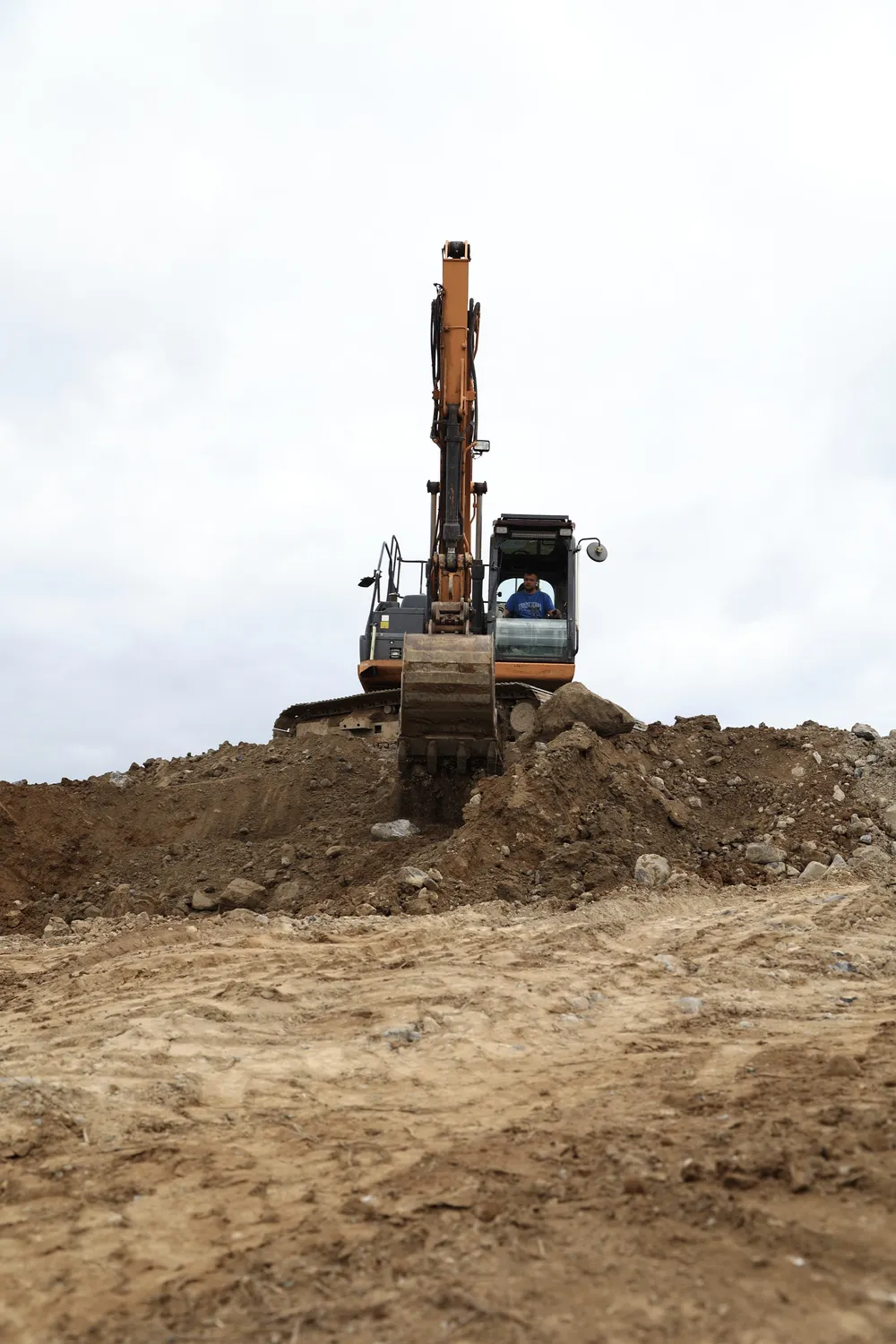 Excavator crossing newly graded earth on an open house site