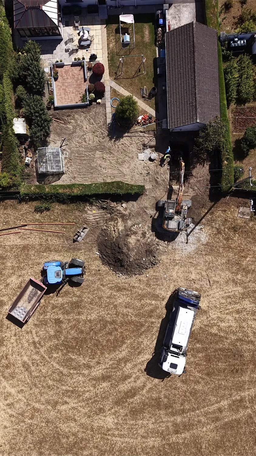 Aerial view of excavator and site trailer beside a house