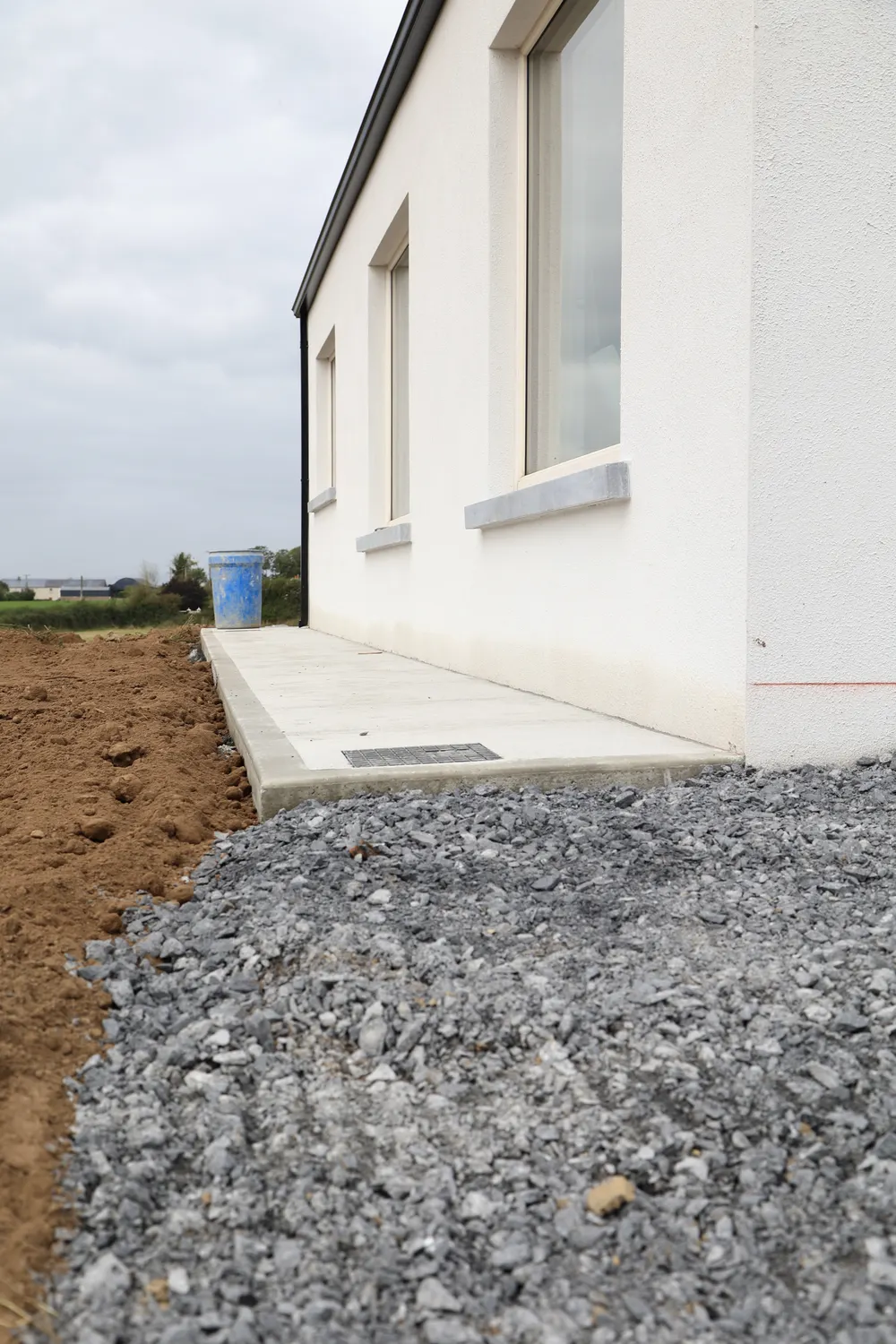 Stone sub-base and newly poured concrete path beside a house