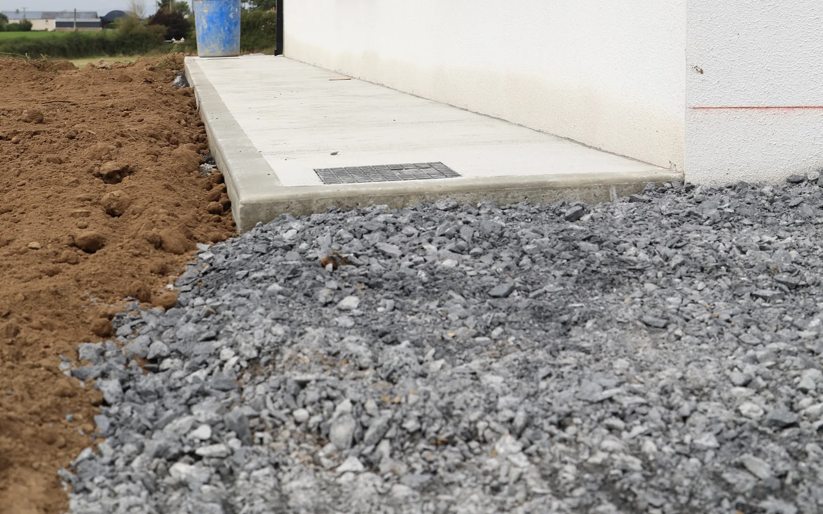 Compacted stone sub-base and concrete path beside a new building during external works