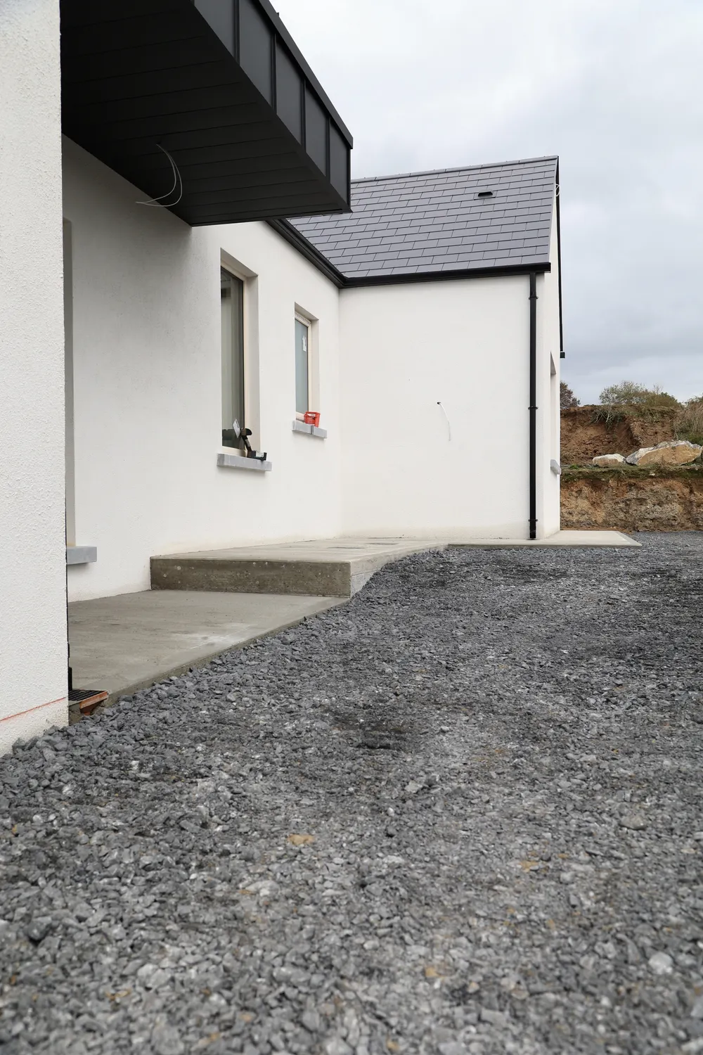 Graded gravel driveway and concrete entrance outside a new house