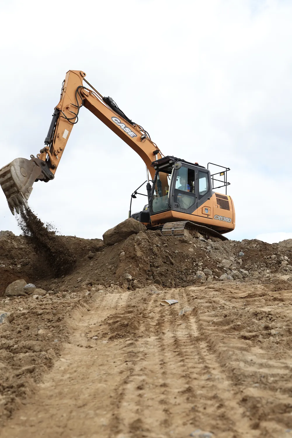 Excavator digging into a low bank of soil on a cleared site