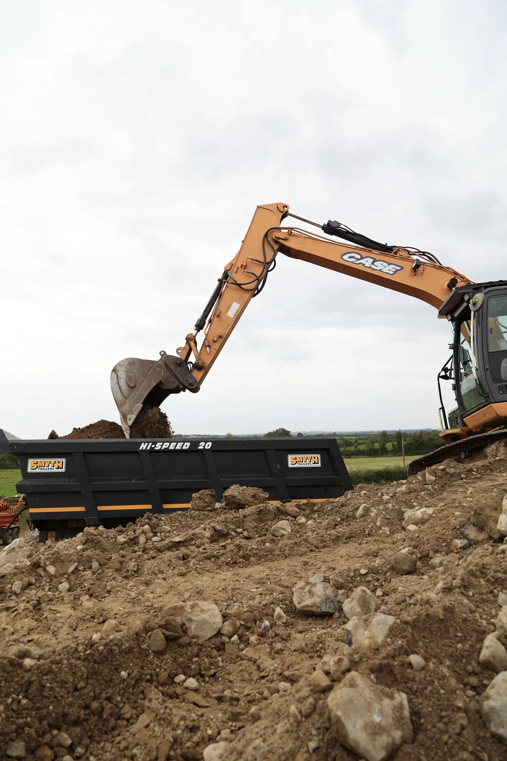 Excavator placing soil in a trailer during ground preparation